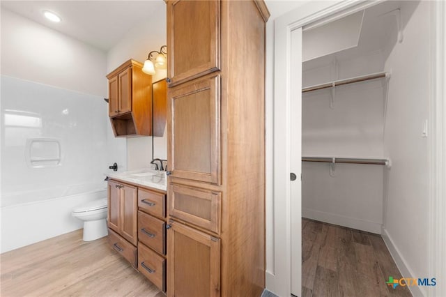 full bathroom featuring toilet, vanity, wood-type flooring, and bathing tub / shower combination