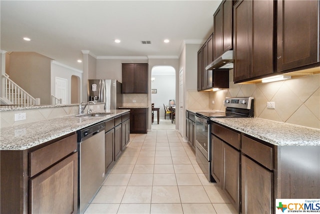 kitchen featuring stainless steel appliances, light tile patterned flooring, dark brown cabinetry, sink, and backsplash