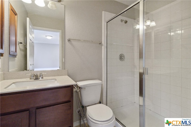 bathroom with toilet, vanity, and a shower with shower door