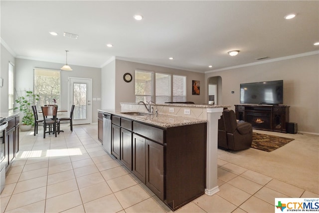 kitchen with crown molding, light carpet, hanging light fixtures, sink, and a kitchen island with sink