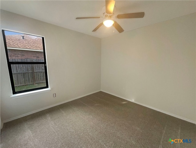 spare room featuring ceiling fan, dark carpet, and plenty of natural light