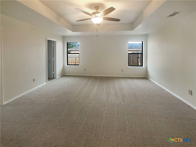 carpeted spare room featuring ceiling fan and a raised ceiling