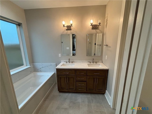 full bath with tile patterned floors, a garden tub, a sink, and a healthy amount of sunlight