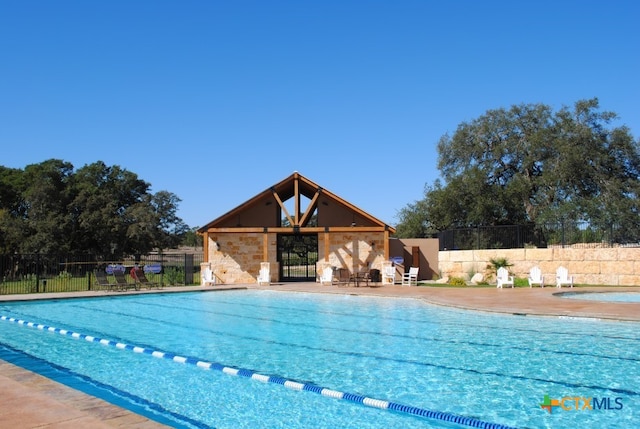 community pool with a patio area and fence
