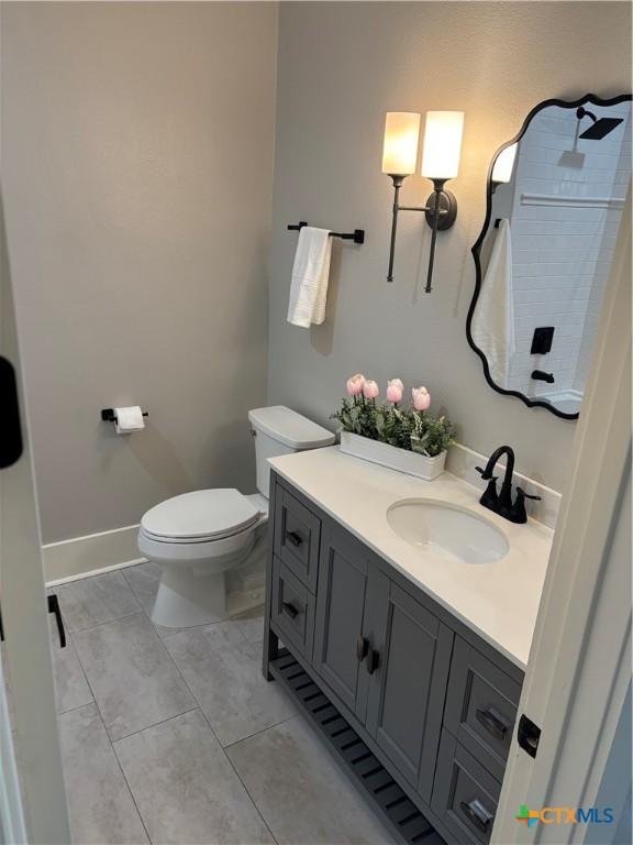 full bath featuring tiled shower, toilet, baseboards, tile patterned flooring, and vanity
