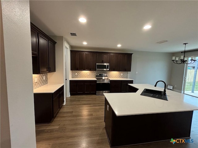 kitchen with stainless steel appliances, dark wood-style floors, a sink, a large island, and decorative backsplash