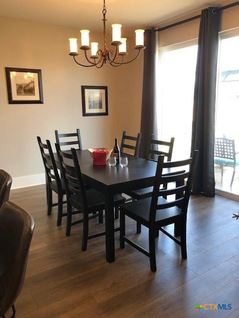 dining space featuring plenty of natural light, a notable chandelier, baseboards, and dark wood-style flooring