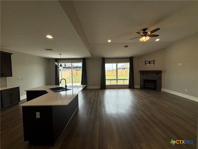 kitchen featuring a fireplace with flush hearth, light countertops, baseboards, and a sink