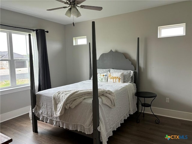 bedroom featuring baseboards, wood finished floors, and multiple windows