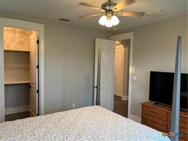 bedroom with baseboards, a ceiling fan, wood finished floors, and visible vents