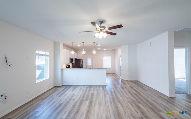 unfurnished living room featuring ceiling fan and light hardwood / wood-style floors