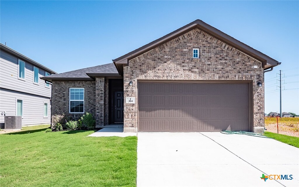 view of front of home with a garage, a front lawn, and central AC