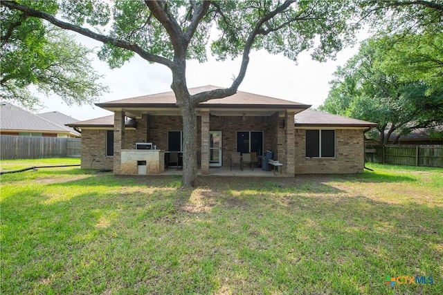 back of property featuring a lawn, a fenced backyard, a patio area, and brick siding