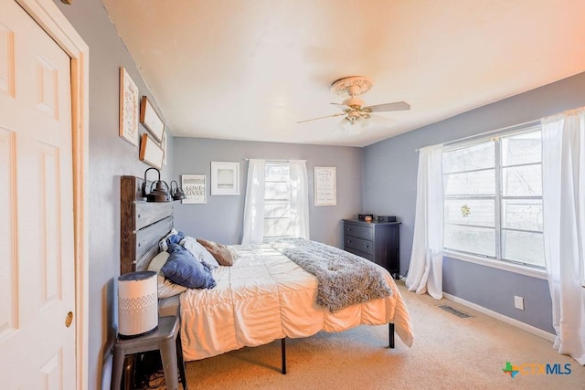 bedroom featuring multiple windows, ceiling fan, and light colored carpet