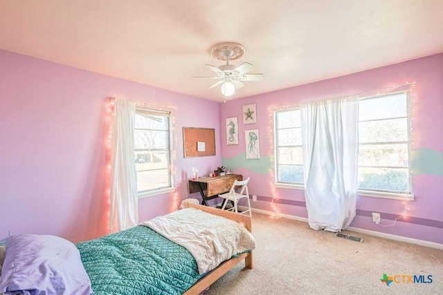 carpeted bedroom featuring ceiling fan and multiple windows