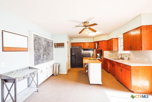 kitchen with ceiling fan, black fridge with ice dispenser, a kitchen island, and sink