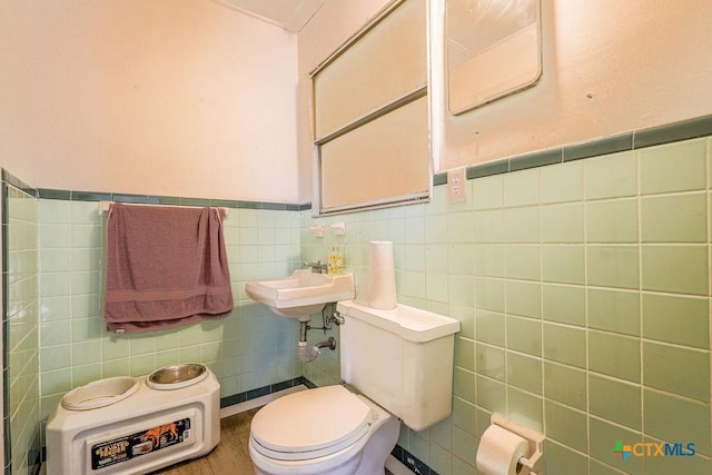 bathroom featuring toilet, tile walls, and sink