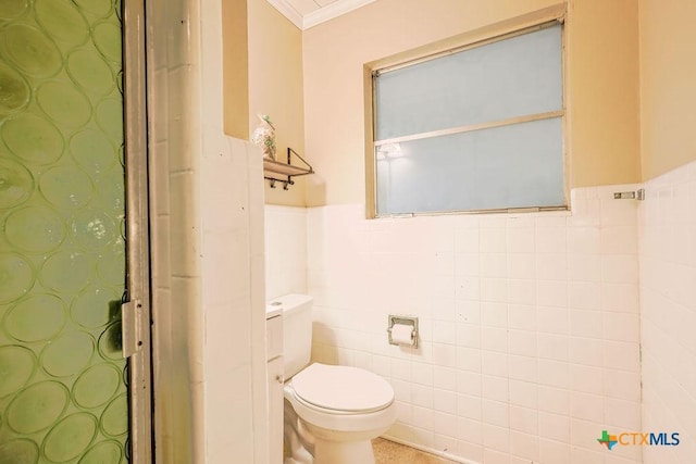 bathroom featuring toilet, ornamental molding, and tile walls