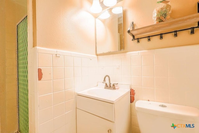 bathroom with vanity, toilet, and tile walls