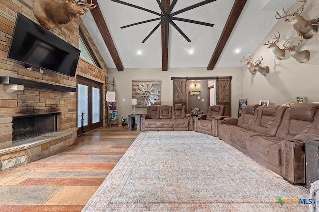 living area with wood finished floors, lofted ceiling with beams, a stone fireplace, french doors, and a barn door