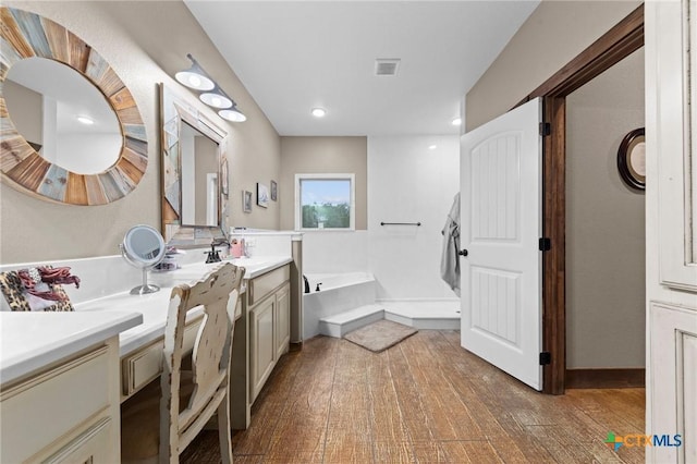 full bathroom with visible vents, a bath, vanity, and hardwood / wood-style flooring