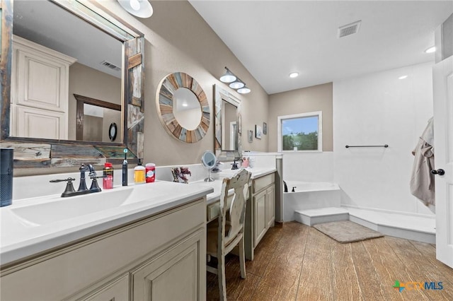 bathroom featuring vanity, a bath, visible vents, and hardwood / wood-style floors