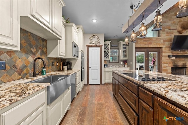 kitchen featuring glass insert cabinets, black electric stovetop, light stone counters, hardwood / wood-style flooring, and a sink