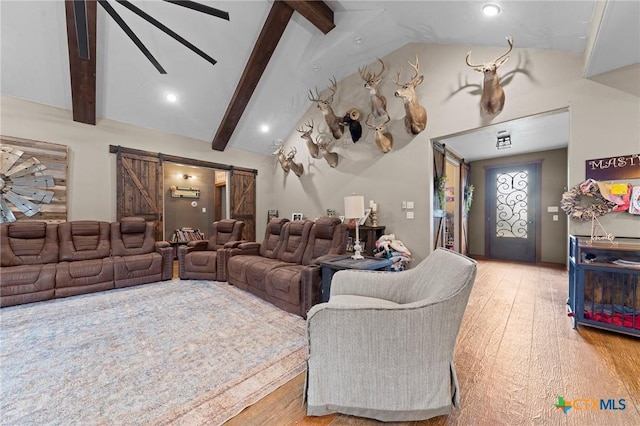 living room with a barn door, vaulted ceiling with beams, and light wood-type flooring