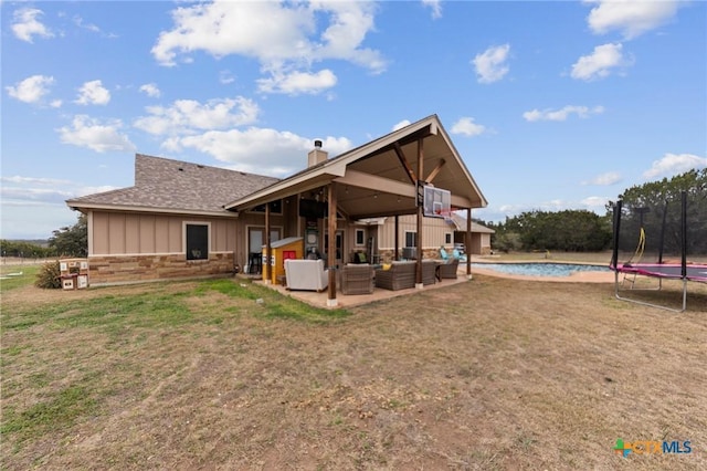 rear view of property with a patio area, a lawn, outdoor lounge area, and a trampoline