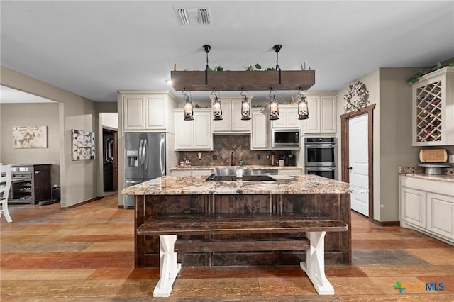 kitchen featuring tasteful backsplash, visible vents, appliances with stainless steel finishes, and a kitchen bar