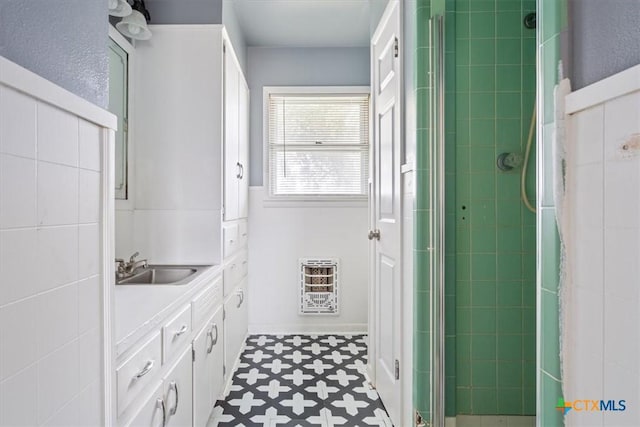 bathroom with a shower with door, vanity, and heating unit