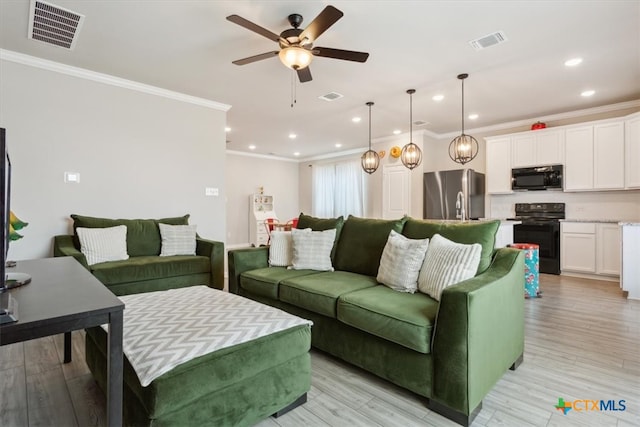 living room with light hardwood / wood-style floors, ceiling fan, and crown molding