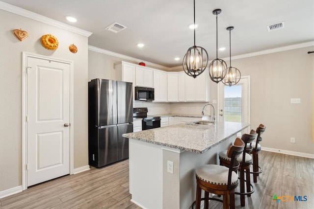 kitchen featuring white cabinetry, appliances with stainless steel finishes, light stone countertops, sink, and light hardwood / wood-style floors