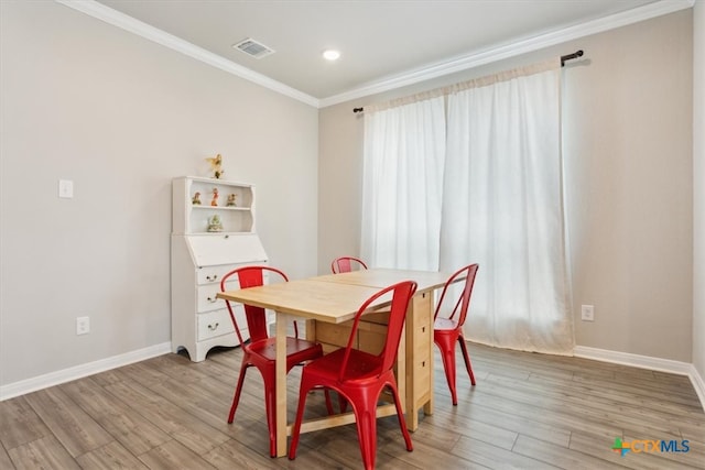 dining area with wood-type flooring and ornamental molding