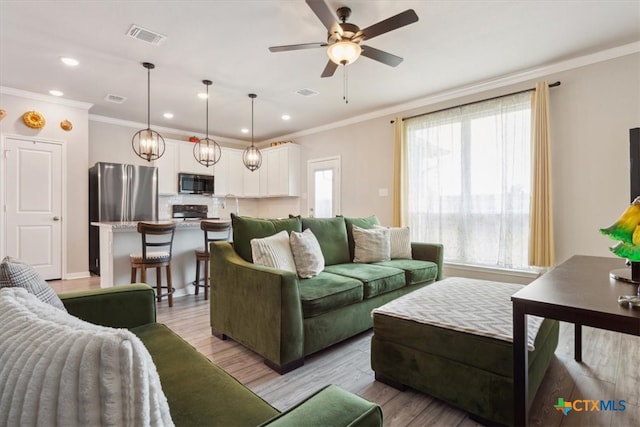 living room featuring ceiling fan, light hardwood / wood-style floors, and crown molding