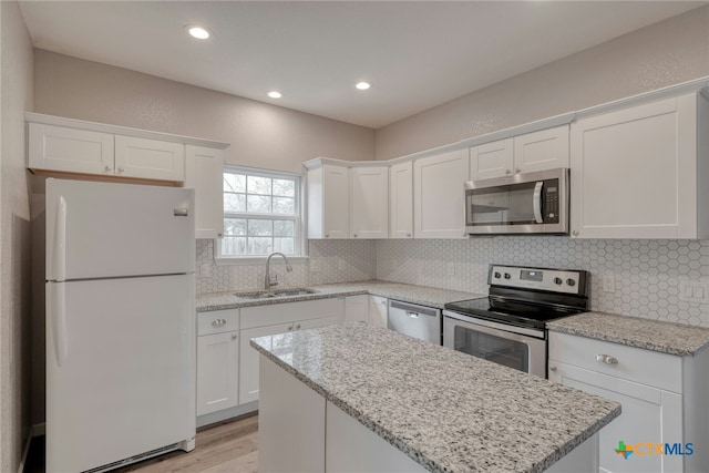 1408 Armstrong St, Luling, TX 78648 - kitchen featuring appliances with stainless steel finishes, white cabinetry, a kitchen island, backsplash, and recessed lighting