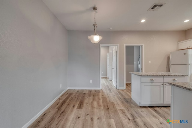 kitchen featuring white cabinets, decorative light fixtures, white fridge, and light stone counters