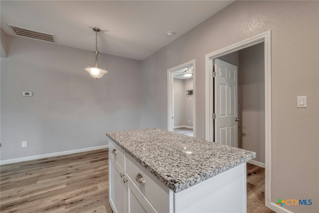 kitchen with a center island, white cabinets, hanging light fixtures, and light hardwood / wood-style floors