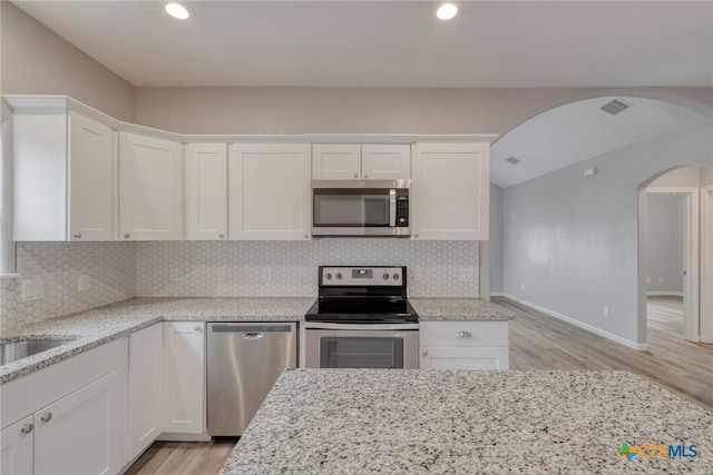 kitchen featuring white cabinets, light stone counters, stainless steel appliances, and tasteful backsplash