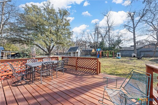 1016 E Elm St, Hillsboro, TX 76645 - deck with outdoor dining area, a fenced backyard, a playground, a trampoline, and a lawn