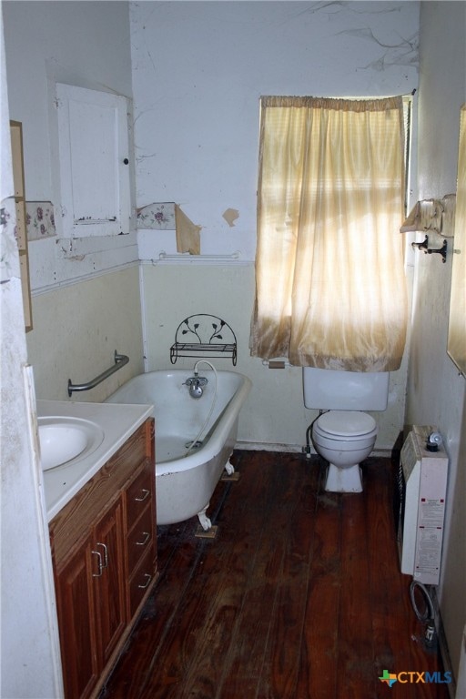 bathroom featuring wood-type flooring, toilet, heating unit, vanity, and a tub to relax in