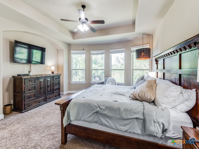 carpeted bedroom featuring ceiling fan and a raised ceiling