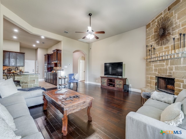 living room featuring dark wood-type flooring, ceiling fan, and a fireplace