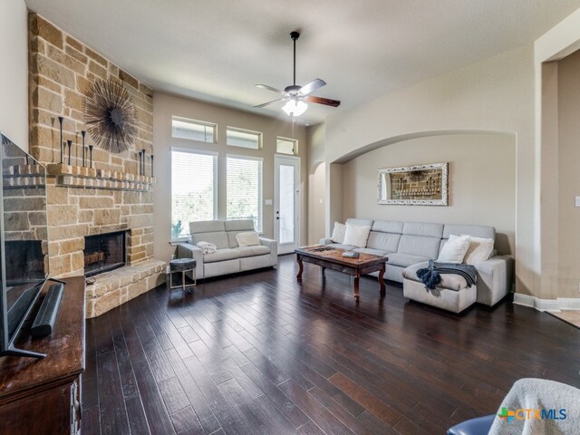 living room featuring a stone fireplace, hardwood / wood-style floors, and ceiling fan