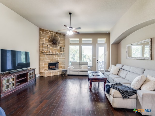 living room with dark wood-type flooring, ceiling fan, and a fireplace