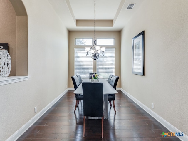 dining room with dark hardwood / wood-style flooring, a chandelier, and a raised ceiling