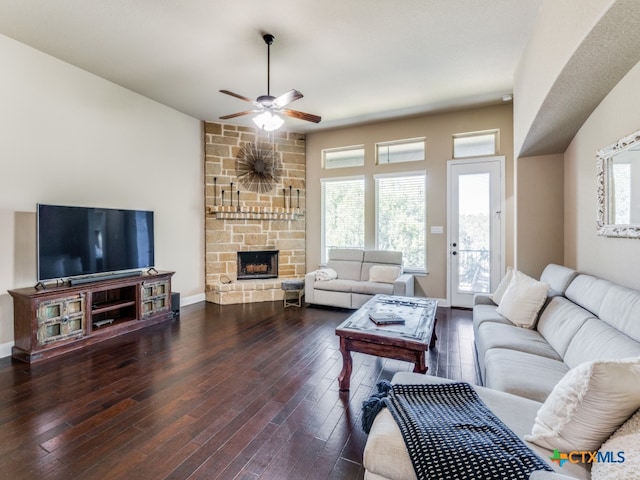 living room with dark wood-type flooring, ceiling fan, plenty of natural light, and a fireplace