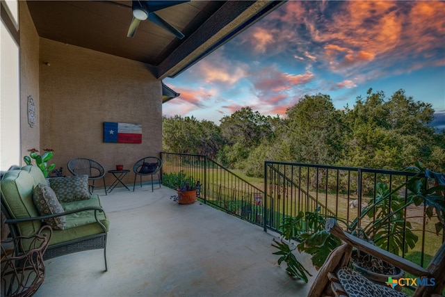 balcony at dusk featuring ceiling fan