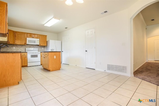 4902 Slate Ct, Killeen, TX 76542 - kitchen featuring white appliances, arched walkways, a kitchen island, dark countertops, and decorative backsplash