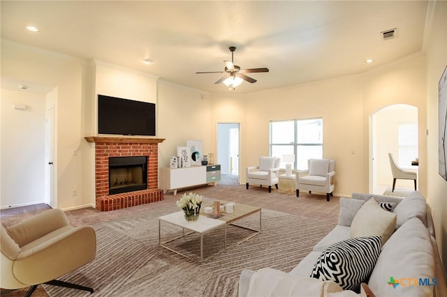 4902 Slate Ct, Killeen, TX 76542 - carpeted living room featuring arched walkways, ceiling fan, a fireplace, ornamental molding, and baseboards